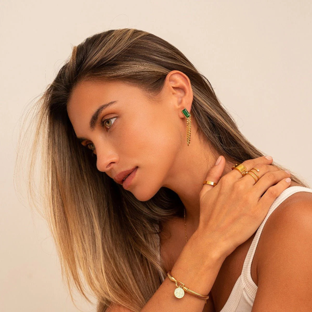 Aros dorados largos con cadena fina y piedra rectangular verde esmeralda en baño de oro 18K de ZAYA