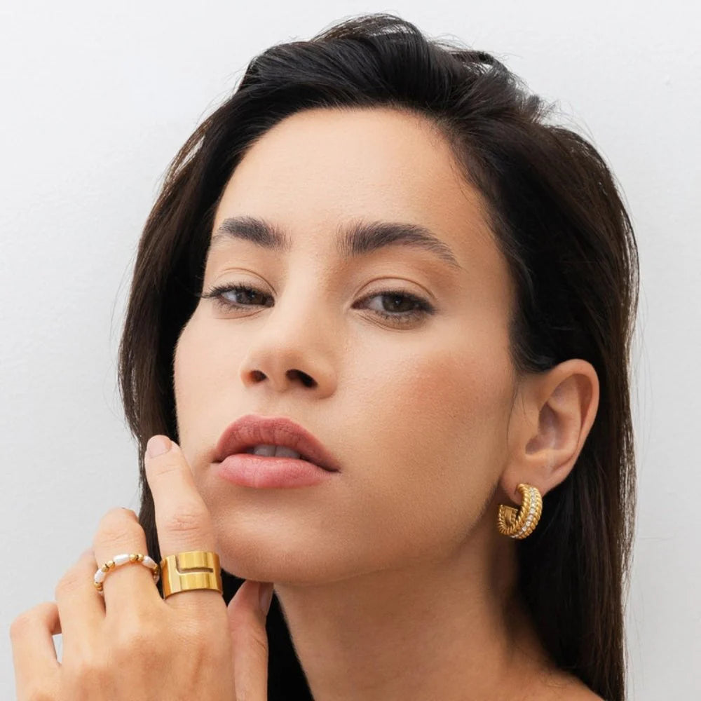 Aros dorados de media argolla con textura trenzada y fila central de circonias, baño de oro 18K en acero inoxidable 316L.