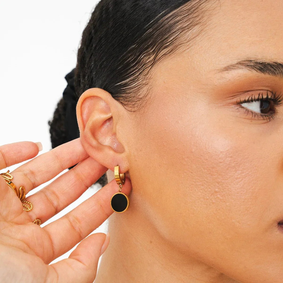 Aros huggie dorados con dije redondo negro estilo ónix, baño de oro 18K en acero inoxidable 316L.