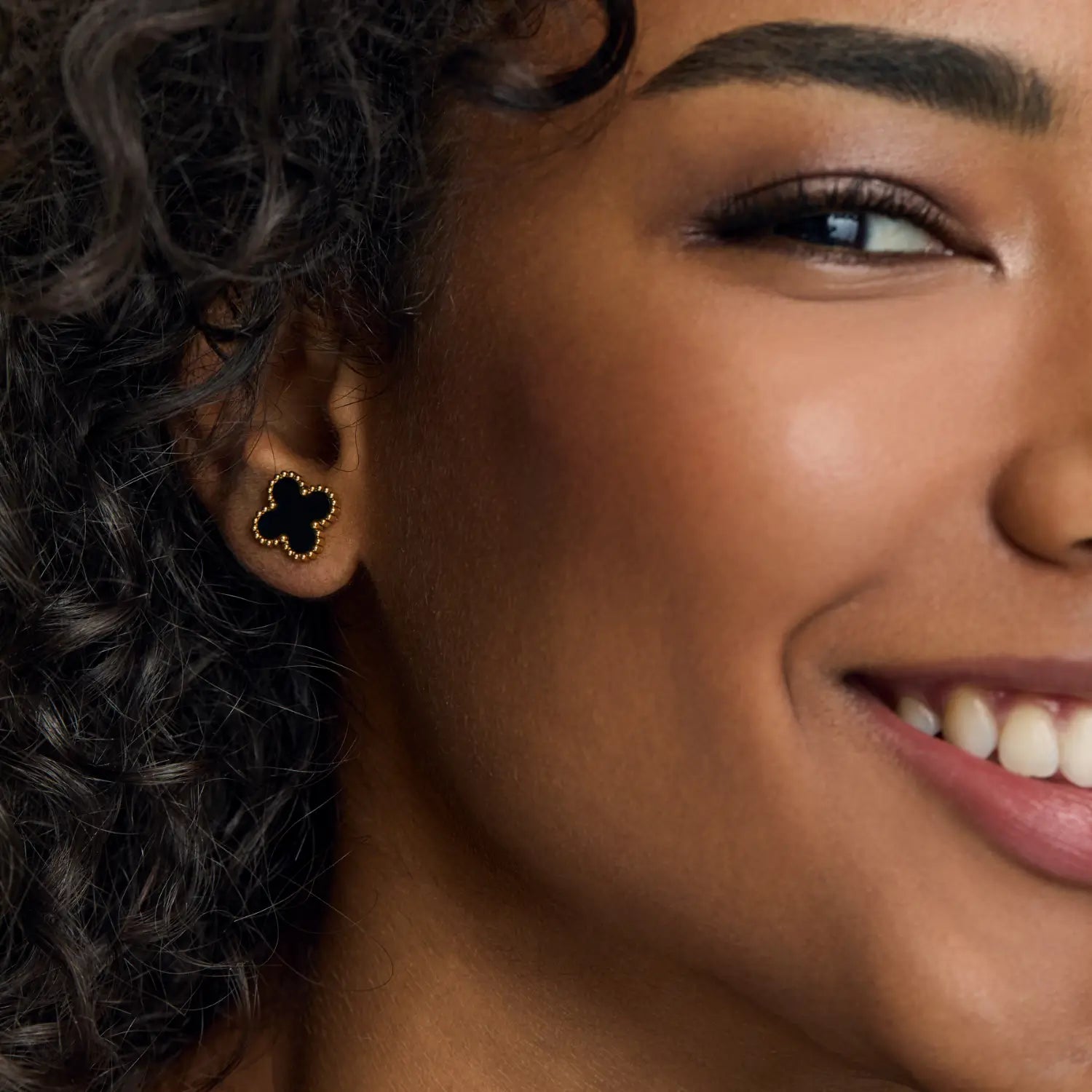 Aros ZAYA tipo stud con trébol negro esmaltado y borde texturizado, baño de oro 18K; hipoalergénicos, a prueba de agua y con garantía de por vida.