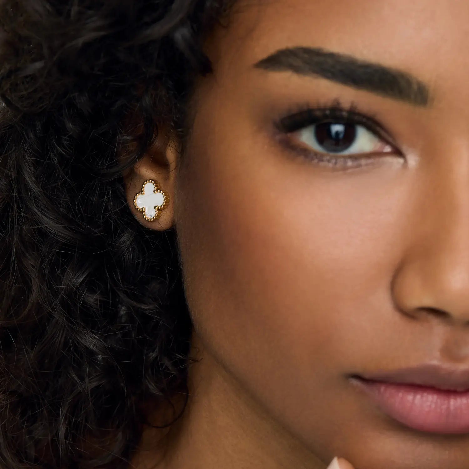 Aros ZAYA tipo stud con trébol blanco esmaltado y borde texturizado, baño de oro 18K; hipoalergénicos, a prueba de agua y con garantía de por vida.