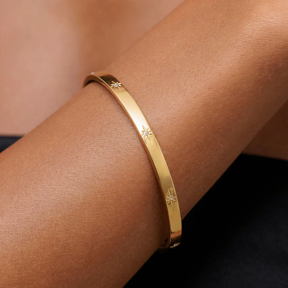 Brazalete Estelar ZAYA rígido con grabados de estrellas y circonias, baño de oro 18K; hipoalergénico, a prueba de agua y con garantía de por vida.
