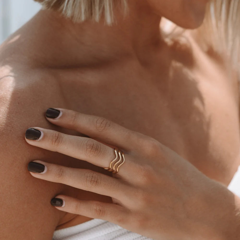 Anillo dorado “Ocean” con diseño de tres ondas, baño de oro 18K sobre acero inoxidable 316L, resistente al agua.