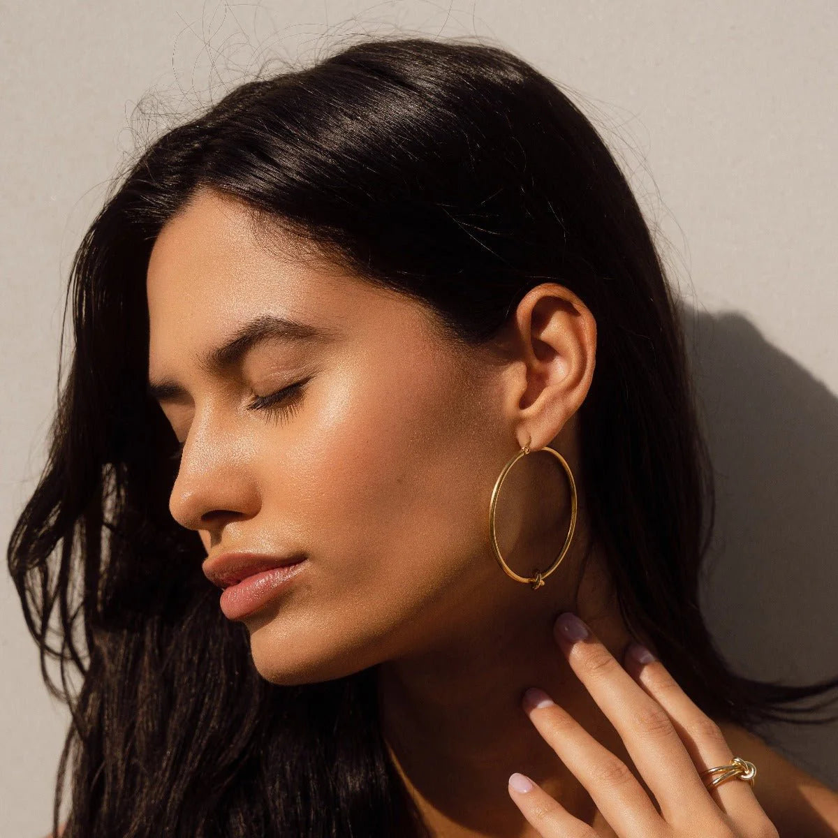 Aros ZAYA de argolla con nudo central, baño de oro 18K; a prueba de agua, hipoalergénicos y con garantía de por vida.