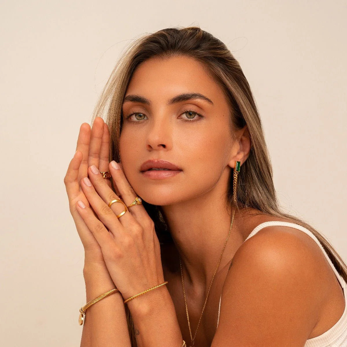 Aros dorados largos con cadena fina y piedra rectangular verde esmeralda en baño de oro 18K de ZAYA