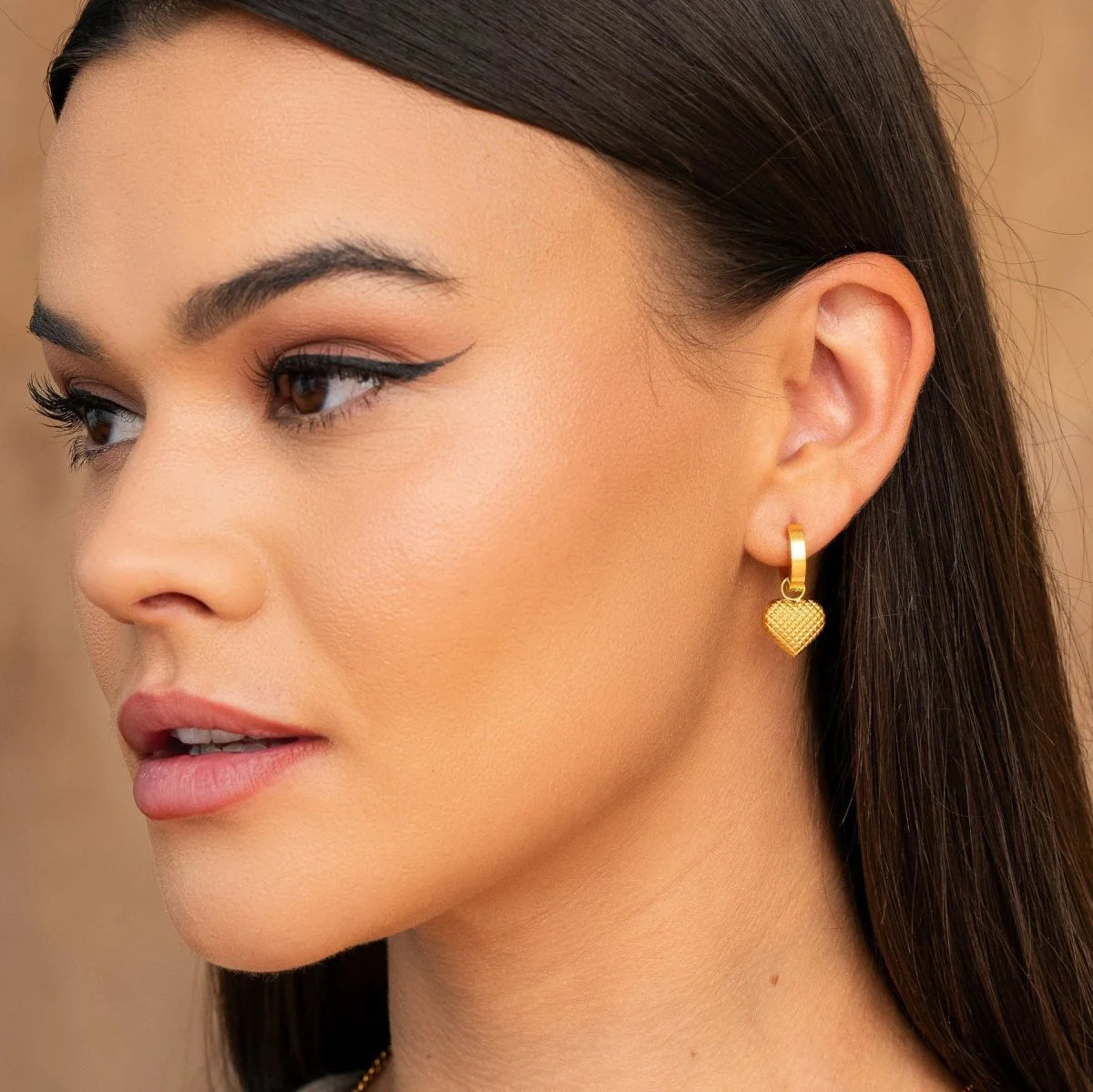 Aros ZAYA huggie con dije de corazón texturizado, baño de oro 18K; a prueba de agua, no se oscurecen, hipoalergénicos y con garantía de por vida.