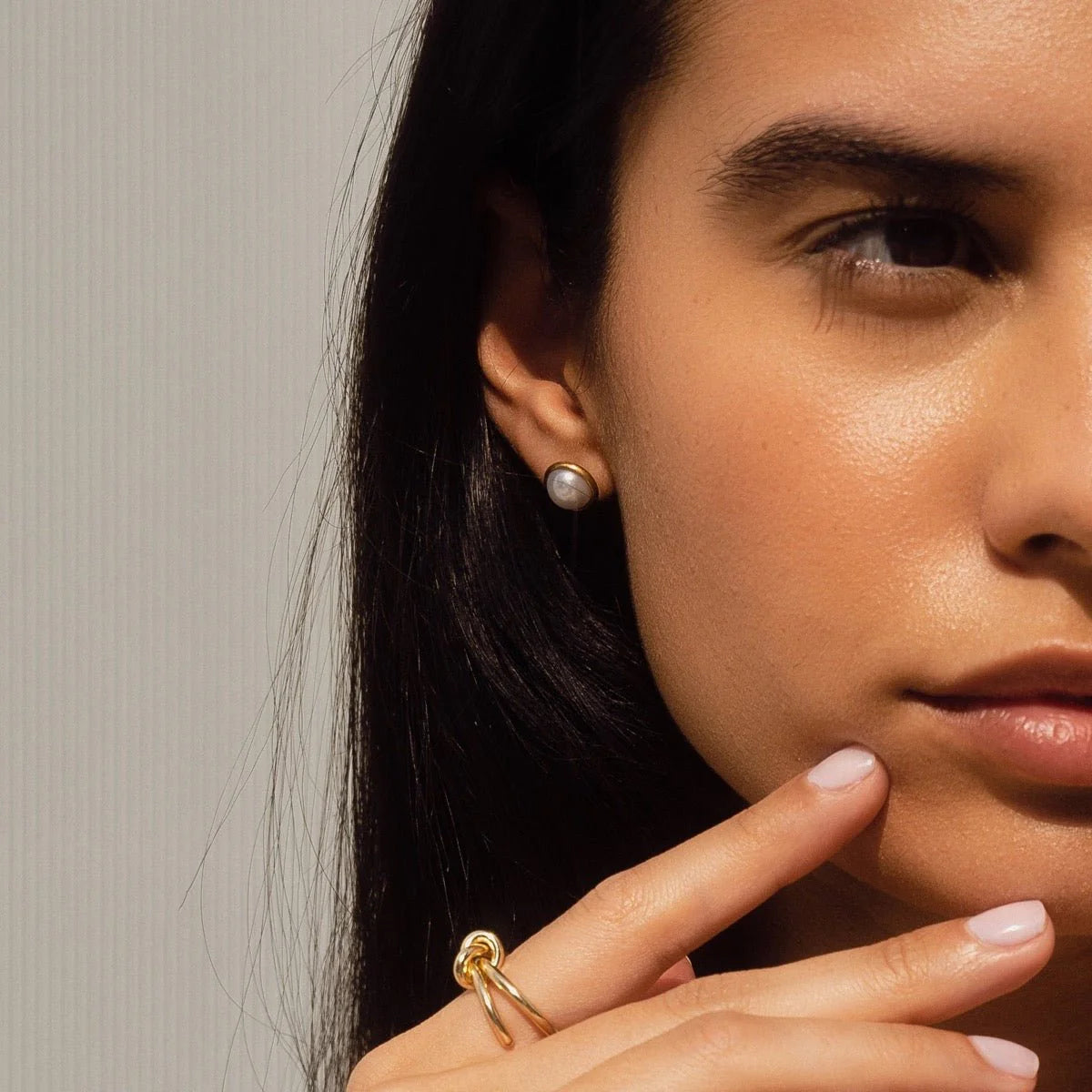 Aros stud dorados con perla redonda blanca en engaste liso, baño de oro 18K sobre acero inoxidable 316L.