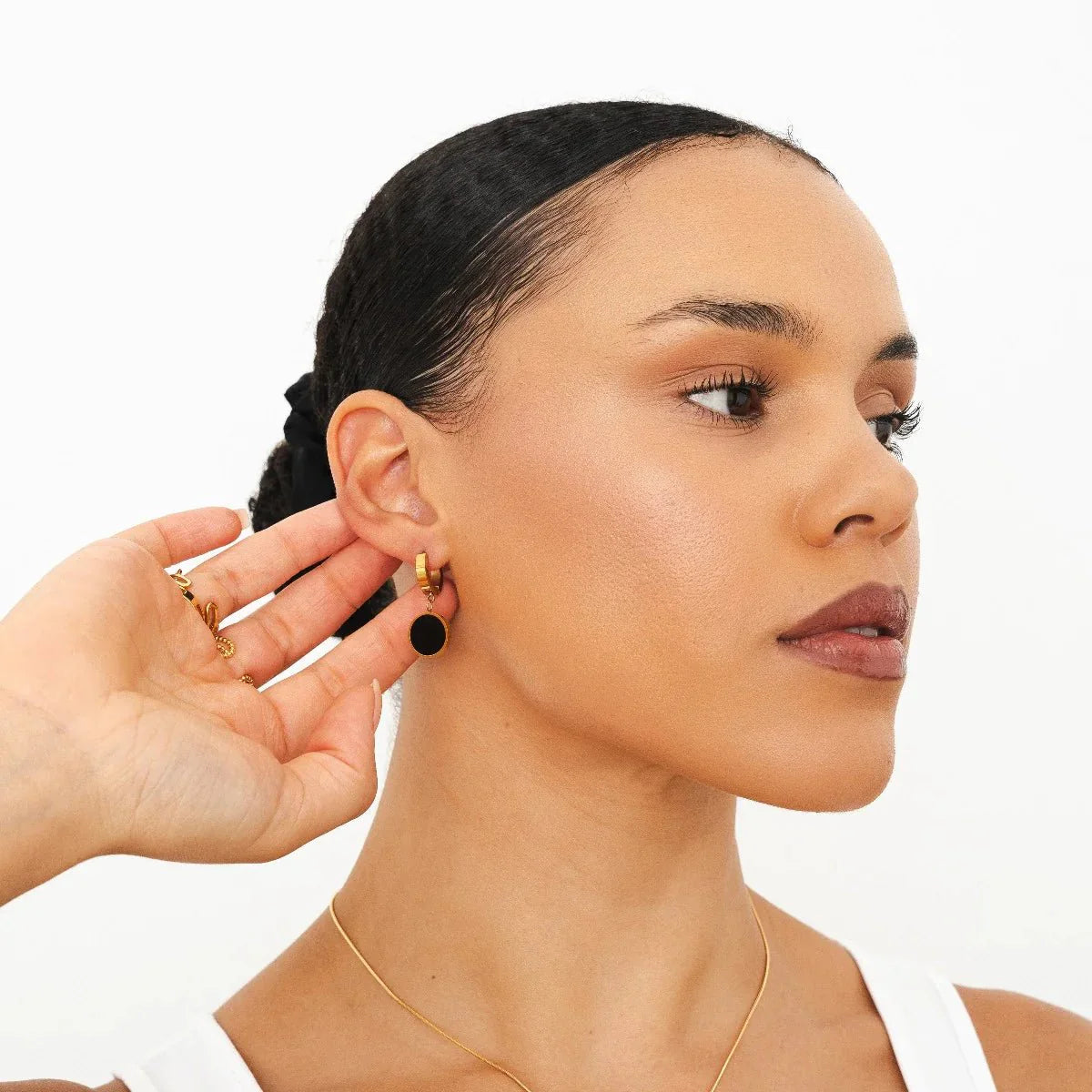 Aros huggie dorados con dije redondo negro estilo ónix, baño de oro 18K en acero inoxidable 316L.