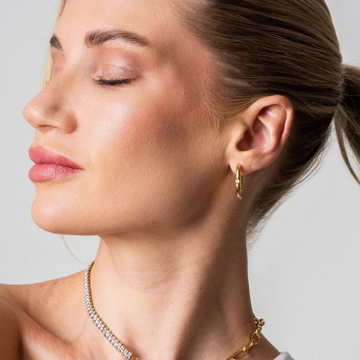 Aros ovalados dorados con pequeña circonia al frente, baño de oro 18K en acero inoxidable 316L.