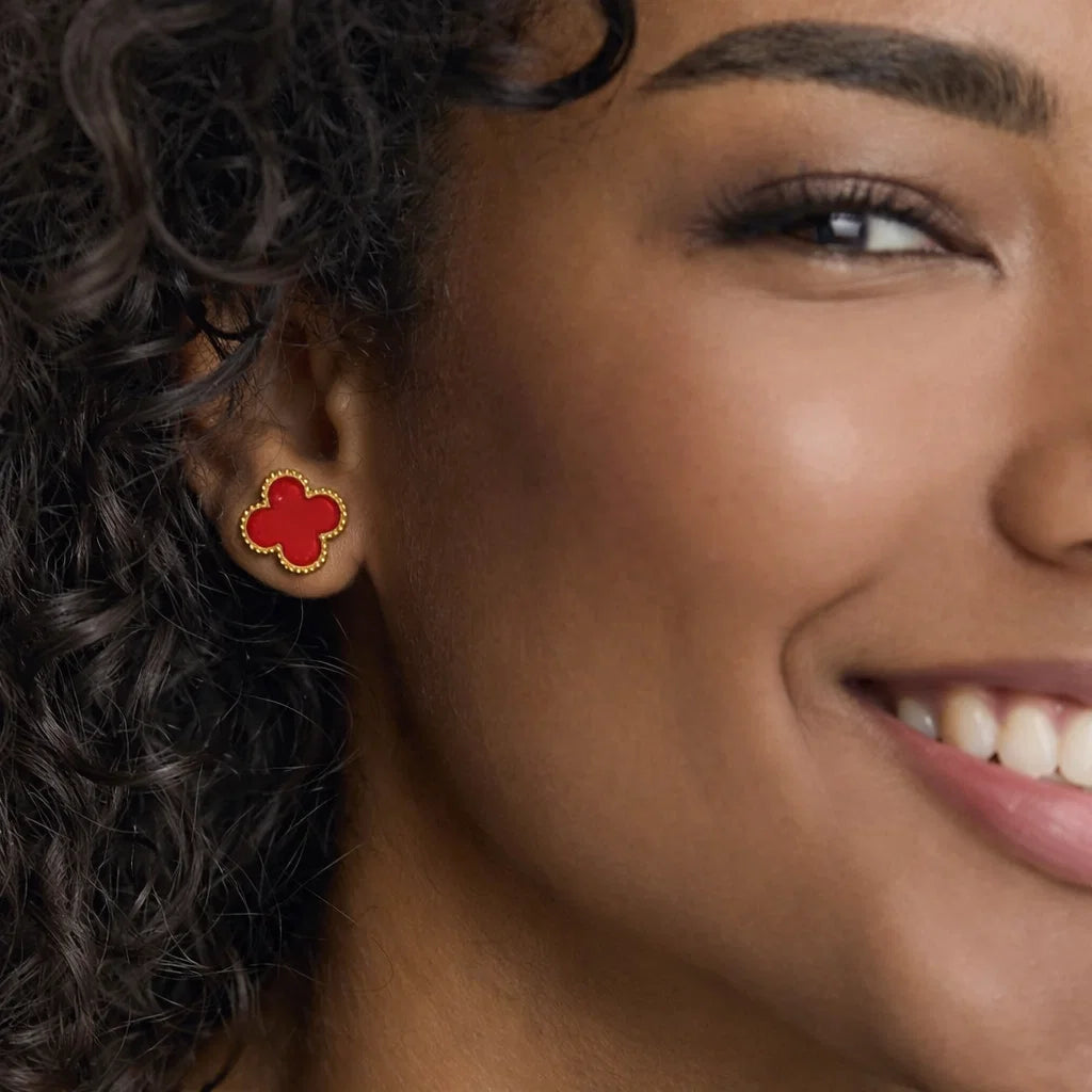 Aros ZAYA tipo stud con trébol rojo esmaltado y borde texturizado; acero inoxidable, baño de oro 18K; hipoalergénicos, a prueba de agua y con garantía de por vida.