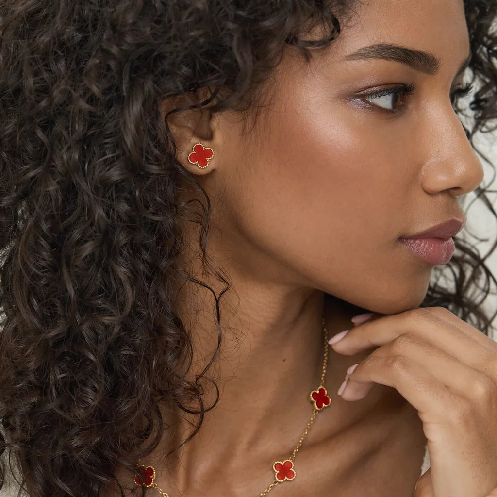 Aros ZAYA tipo stud con trébol rojo esmaltado y borde texturizado; acero inoxidable, baño de oro 18K; hipoalergénicos, a prueba de agua y con garantía de por vida.