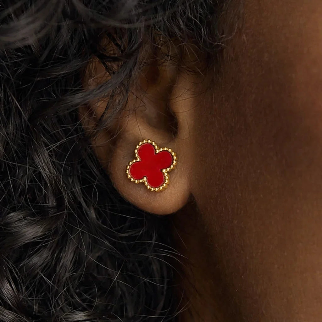 Aros ZAYA tipo stud con trébol rojo esmaltado y borde texturizado; acero inoxidable, baño de oro 18K; hipoalergénicos, a prueba de agua y con garantía de por vida.