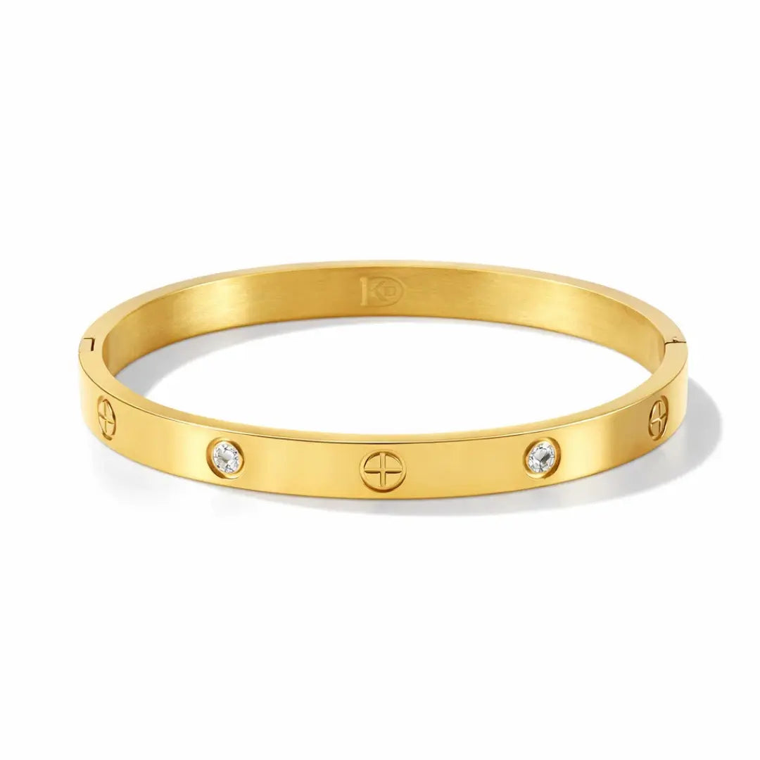 Brazalete rígido con detalles tipo tornillo y zirconias incrustadas. Baño de oro 18K; hipoalergénico, a prueba de agua y con garantía de por vida.