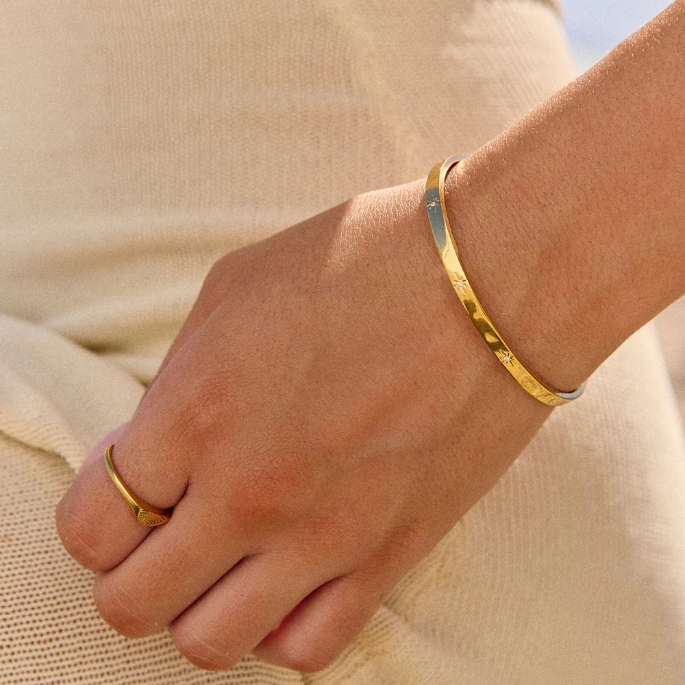 Brazalete Estelar ZAYA rígido con grabados de estrellas y circonias, baño de oro 18K; hipoalergénico, a prueba de agua y con garantía de por vida.