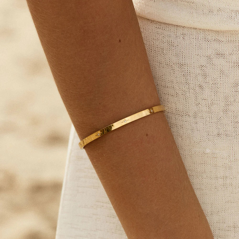 Brazalete Estelar ZAYA rígido con grabados de estrellas y circonias, baño de oro 18K; hipoalergénico, a prueba de agua y con garantía de por vida.