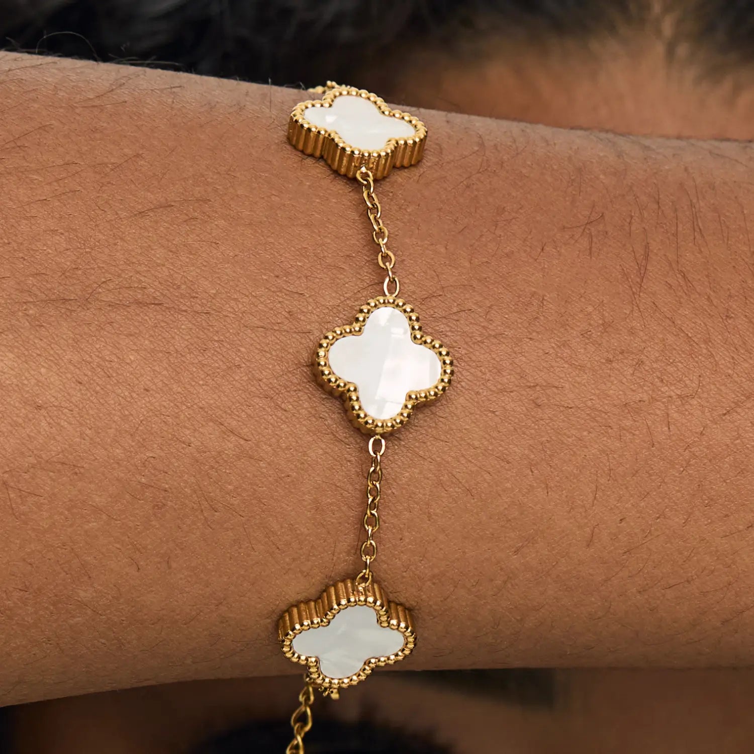Pulsera ZAYA con tréboles blancos esmaltados y borde texturizado, baño de oro 18K; hipoalergénica, a prueba de agua y con garantía de por vida.