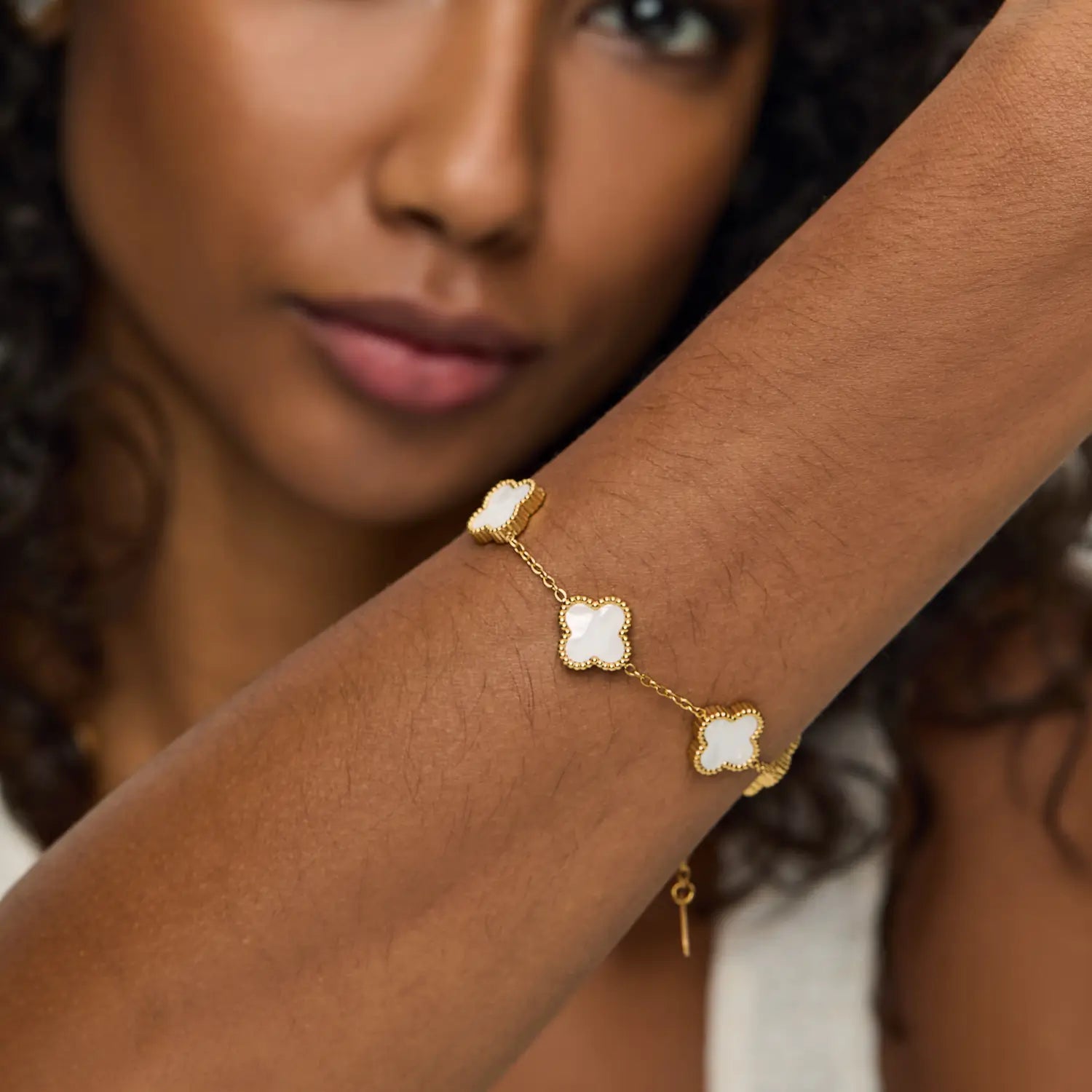 Pulsera ZAYA con tréboles blancos esmaltados y borde texturizado, baño de oro 18K; hipoalergénica, a prueba de agua y con garantía de por vida.