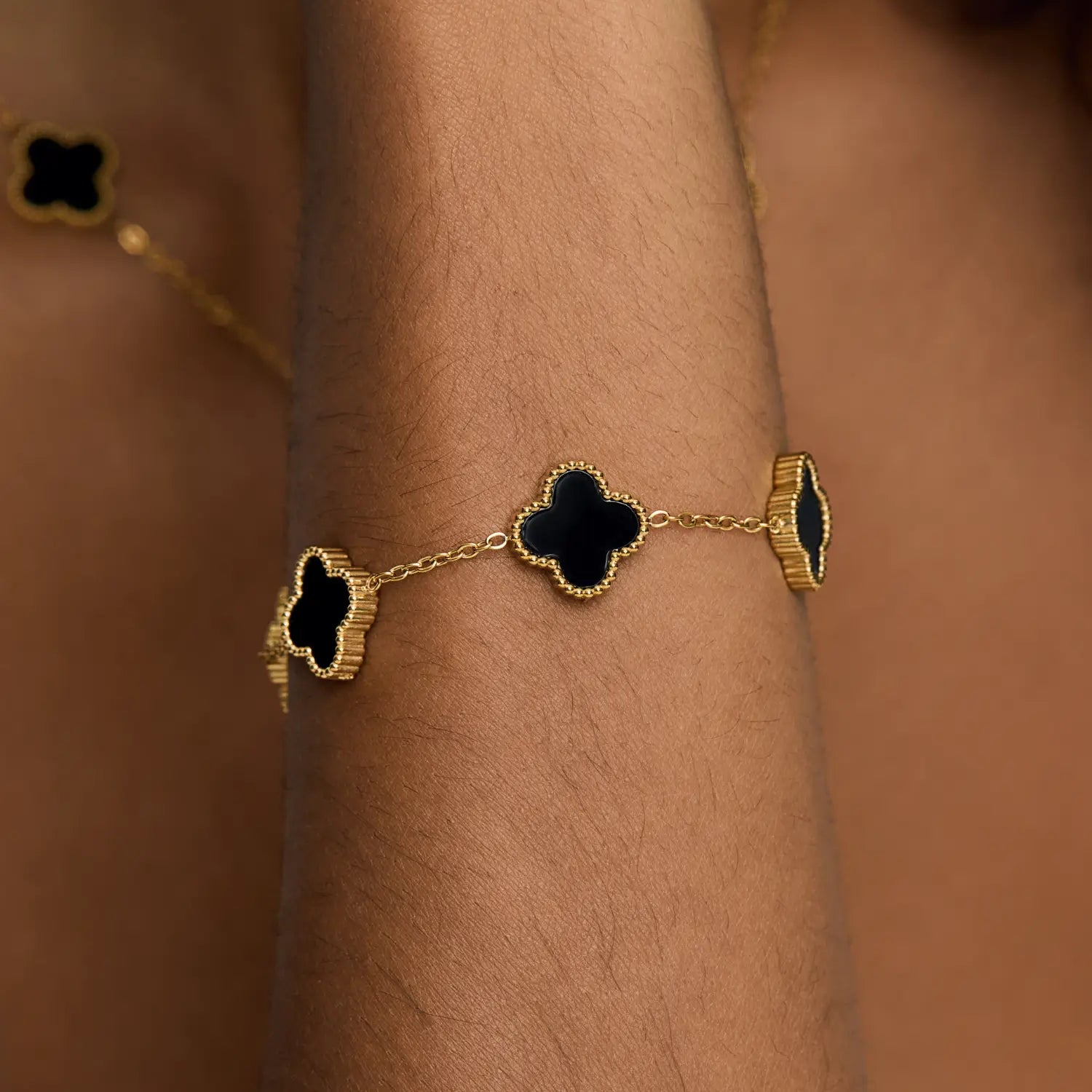 Pulsera ZAYA con tréboles negros esmaltados y borde texturizado, baño de oro 18K; hipoalergénica, a prueba de agua y con garantía de por vida.